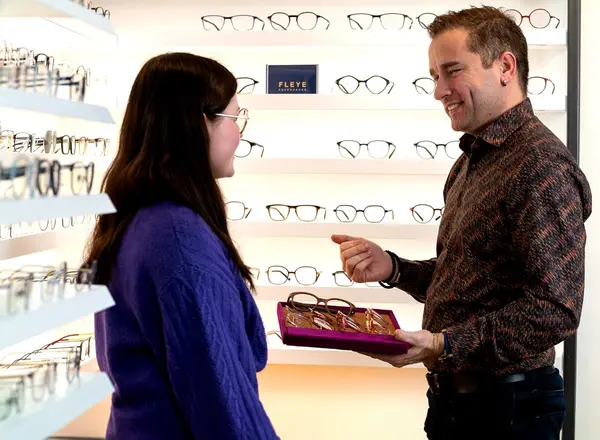 Ein Optiker berät eine Kundin bei der Auswahl von Brillenfassungen im Brillengeschäft.
