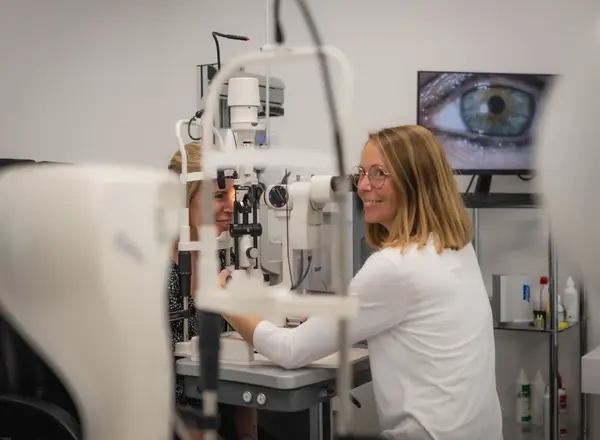 Augenärztin untersucht Patientin mit moderner Augenoptik, Bildschirm zeigt ein Auge.